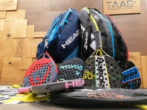 Auf dem Bild sieht man Padel Tennis Equipment: verschiedene Schläger und Taschen
